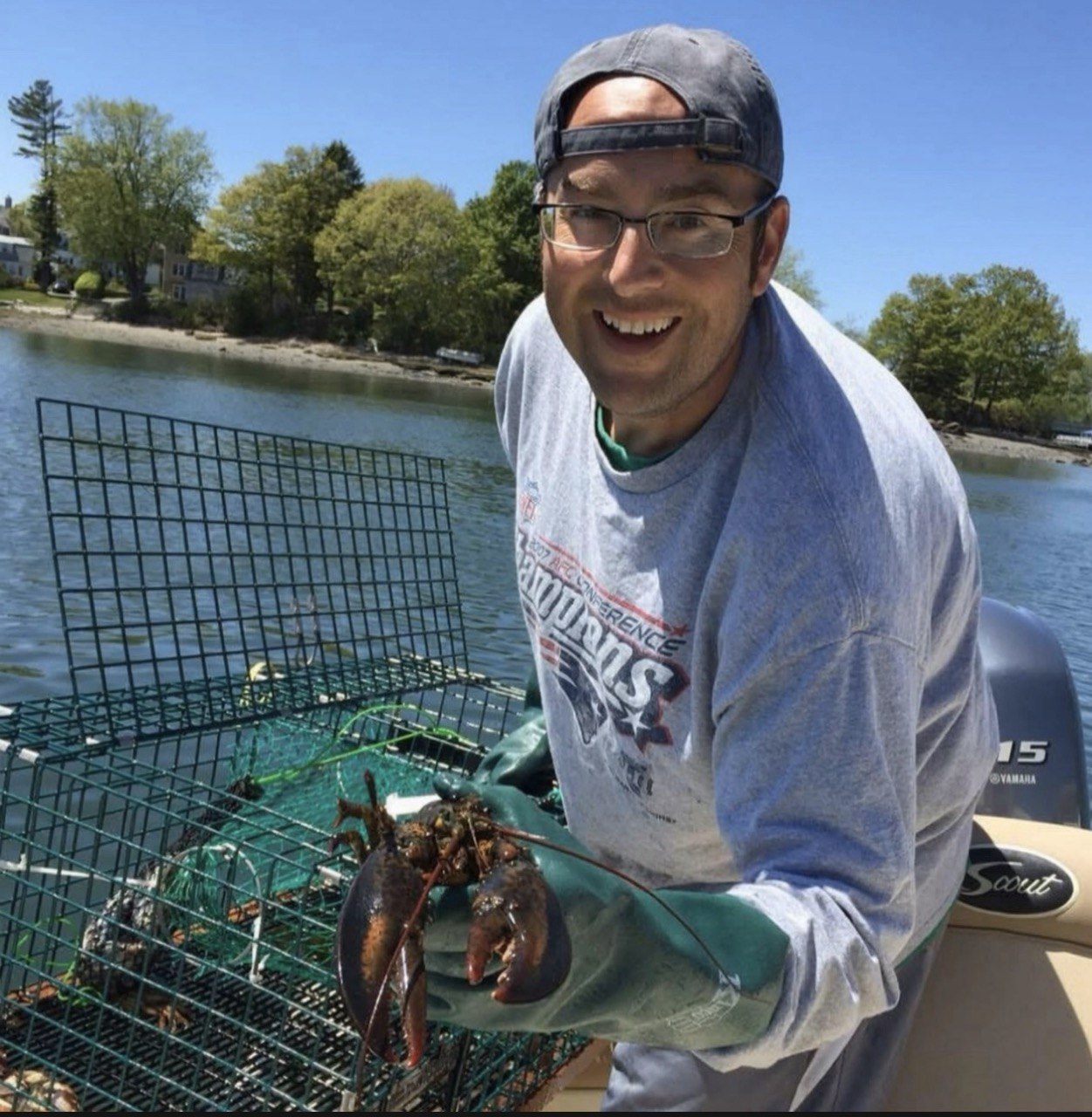 A younger Dave holding a lobster beside a trap on the water